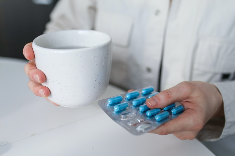 A person holding a cup and pills