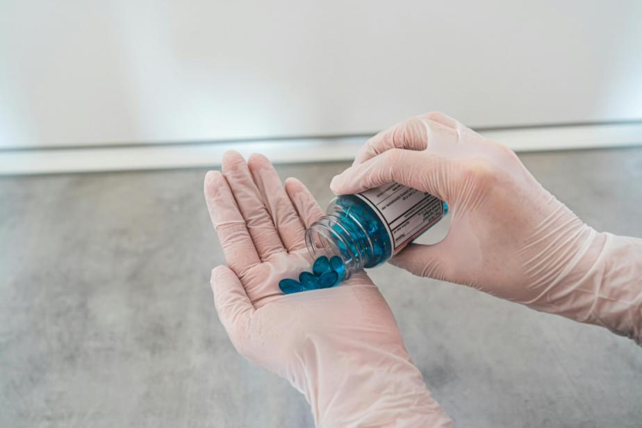 Person pouring down blue pills from a medicine bottle.