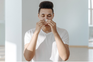 Sick man in a white shirt wiping his nose