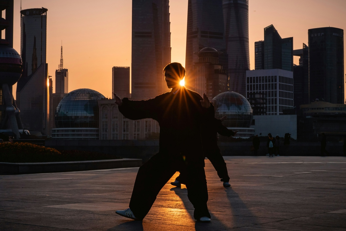 A man performing martial arts in front of buildings