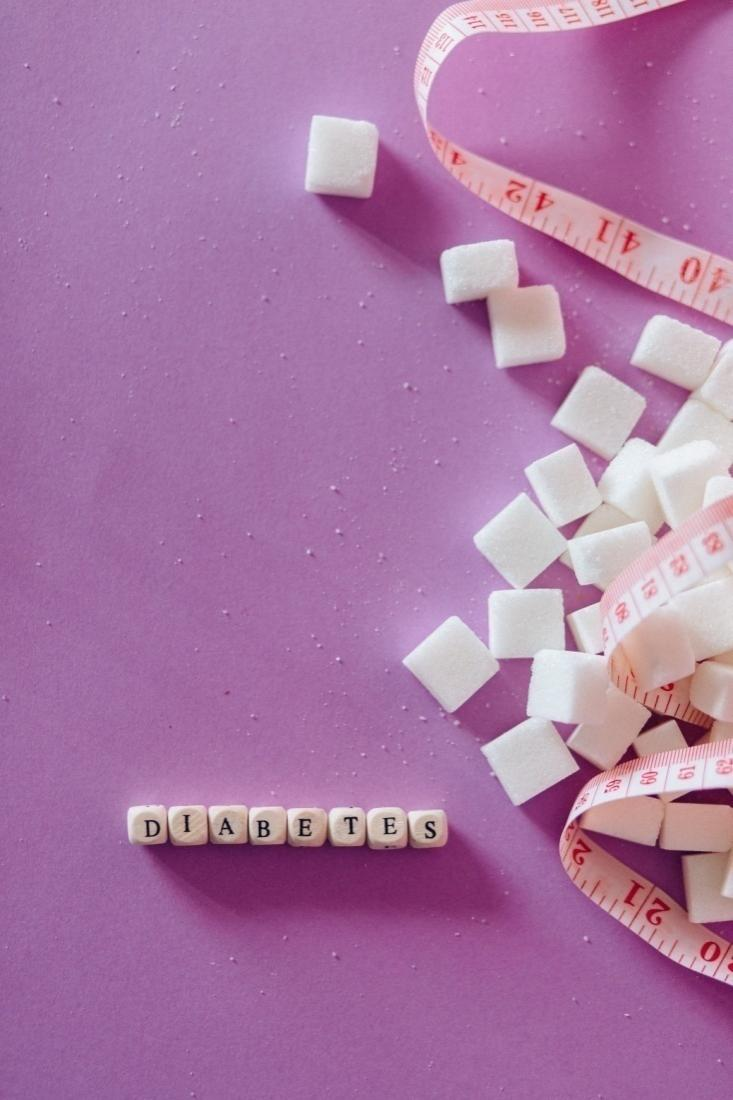  Sugar cubes near diabetes spelled out on dices on a pink surface