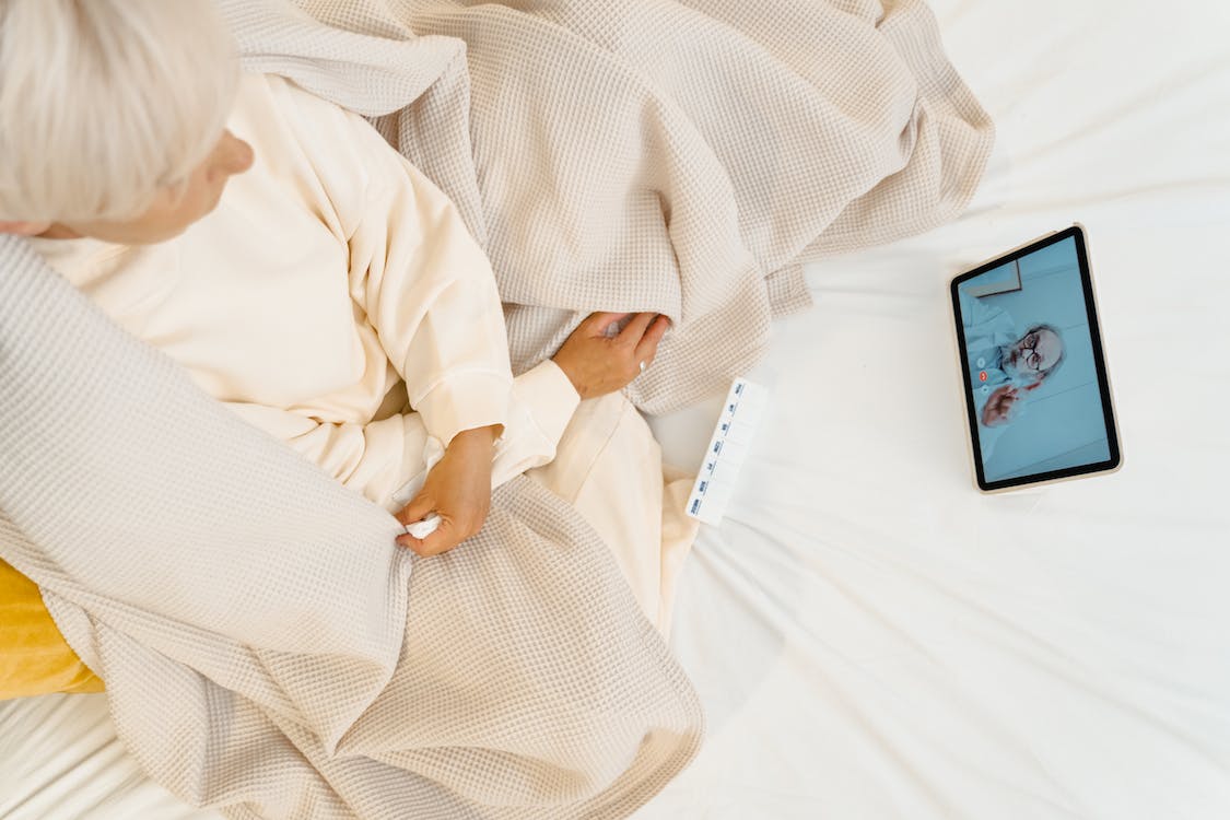 A woman sitting on the bed while consulting an online doctor for pink eye treatment via video call
