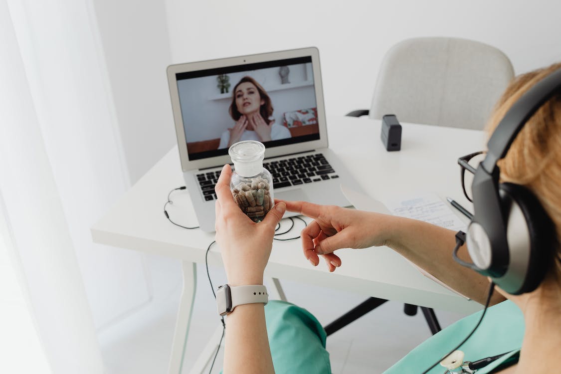 A virtual doctor providing video consultation while holding a medicine bottle