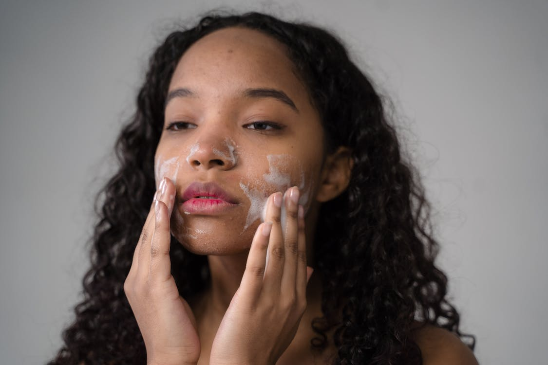 An image of a woman washing her face to treat acne