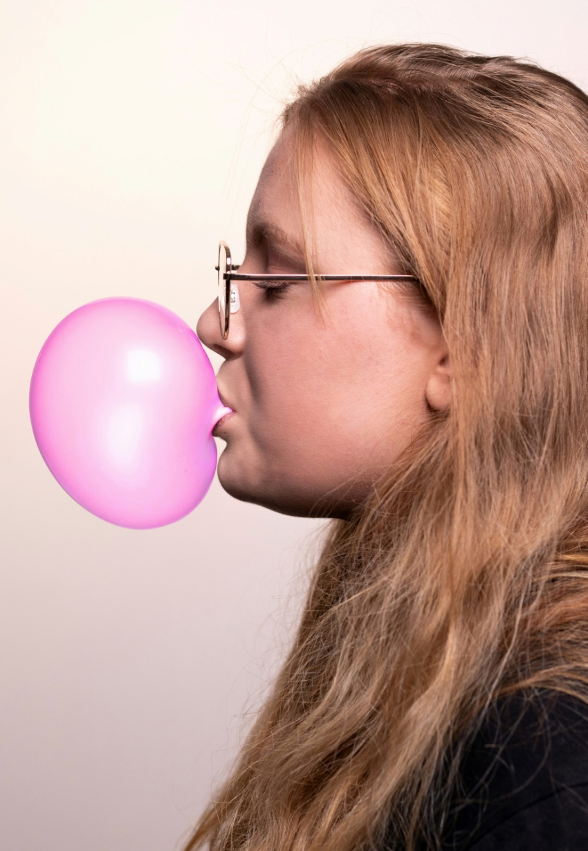 woman blowing a pink chewing gum