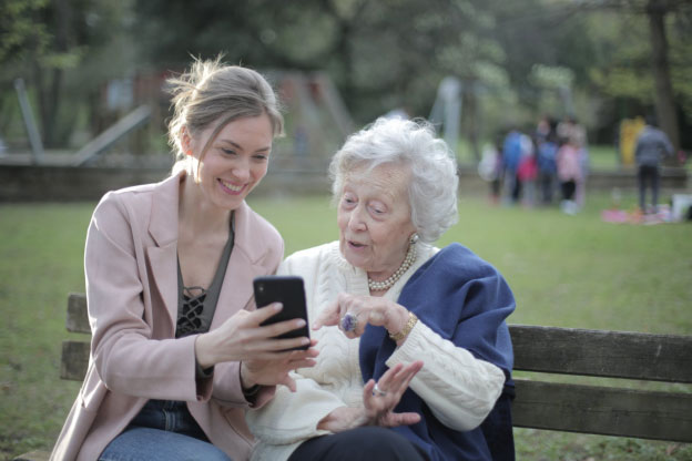 A woman using a smartphone with an elderly woman