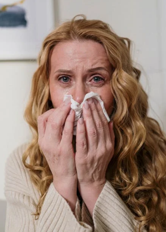 A woman with an allergy covering her mouth and nose with a tissue 