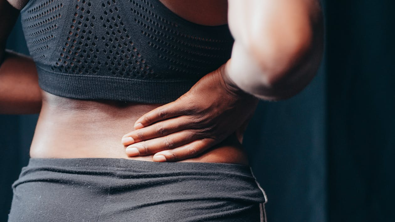 A person holding their lower back in discomfort, showing signs of back pain during daily activities.
