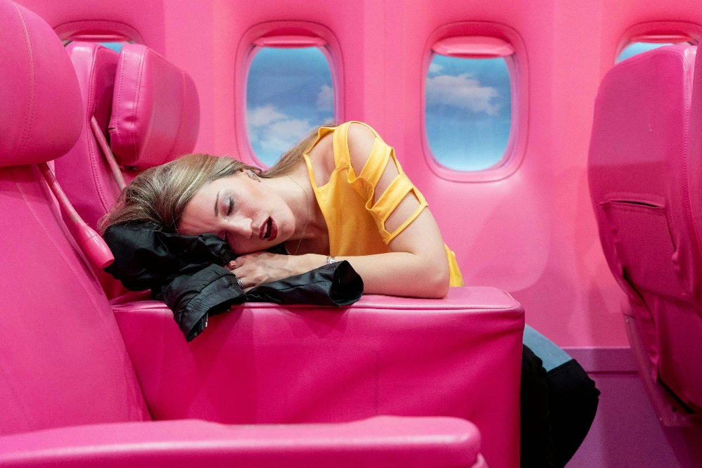 Young woman feeling lightheaded and holding a plastic bag during airplane travel.