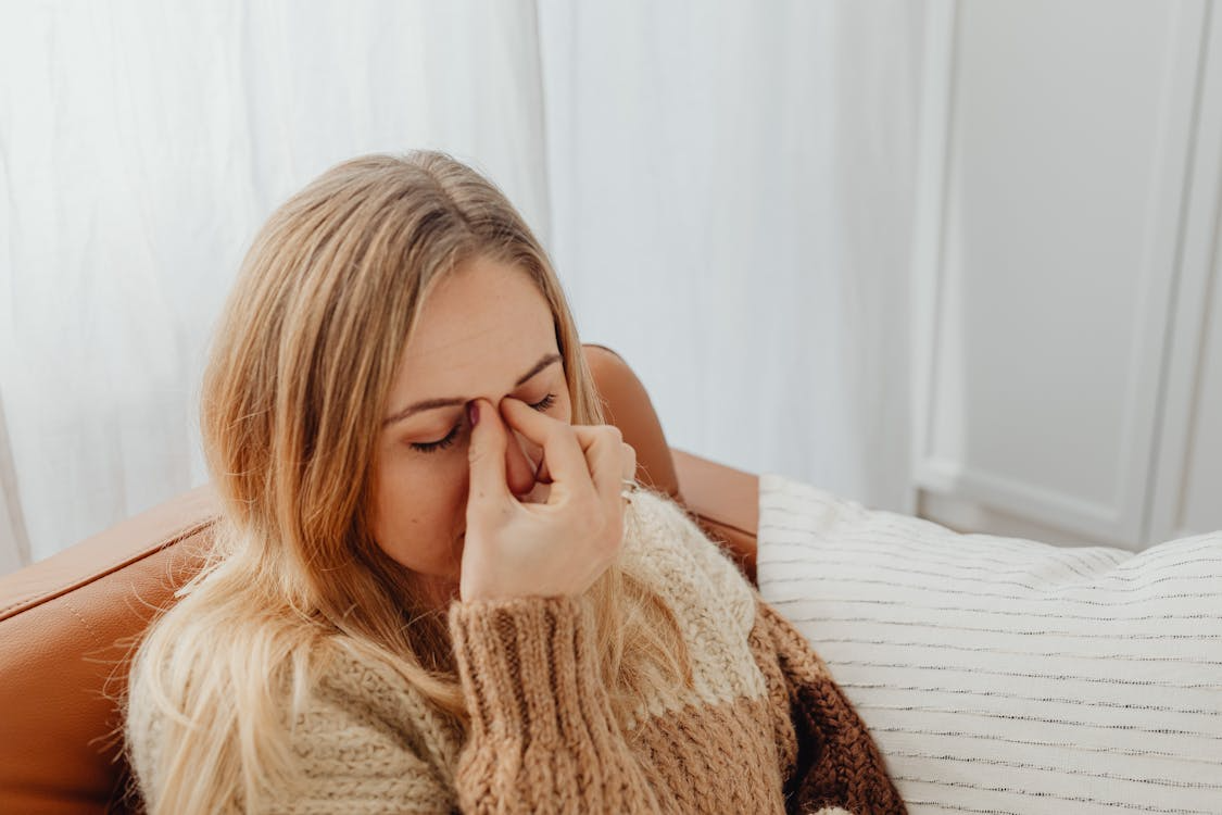 A woman holding her nose and face due to sinus pain and congestion.