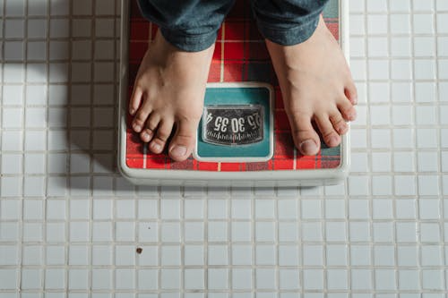 Person standing on a weighing scale at home.