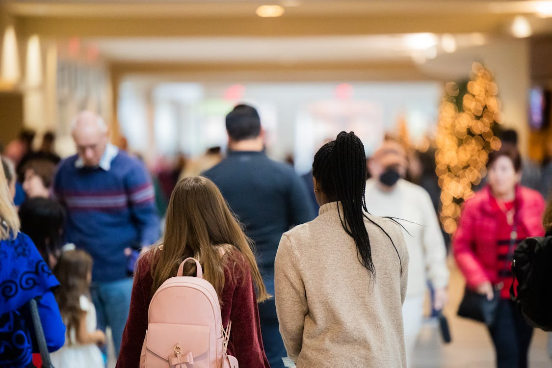 Two girls walking through a crowded holiday market, feeling anxious and overwhelmed by the busy environment.