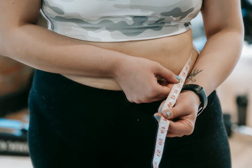 Woman measuring her waist with tape.
