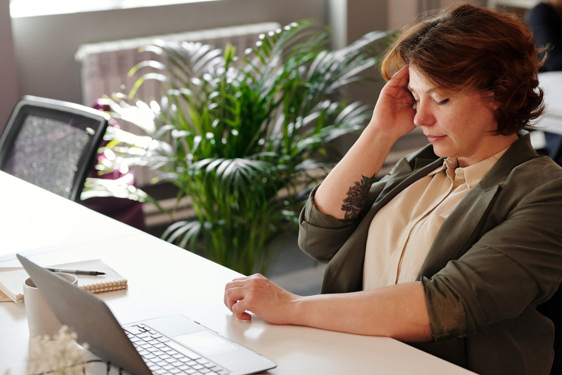 A woman looks fatigued at her desk.