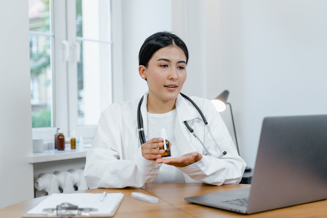 Woman holding a medicine bottle while consulting online.