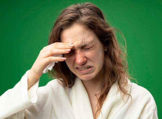 Young girl with closed eyes, wearing a robe, putting her hand on her forehead.
