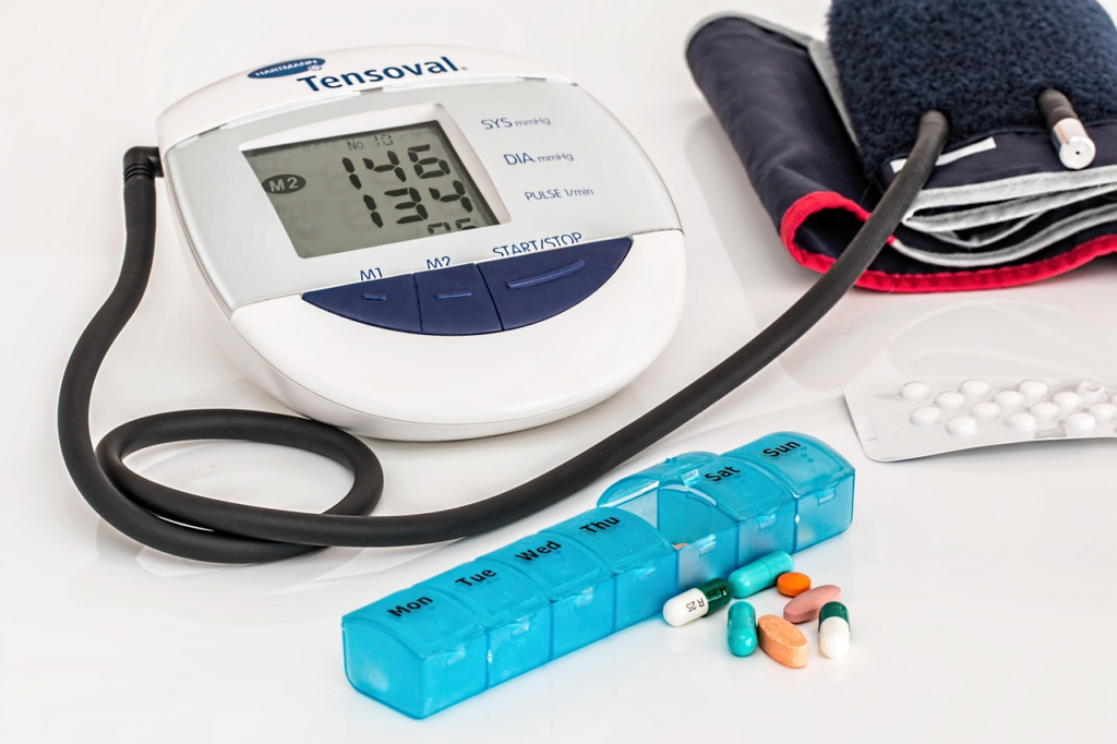 Digital blood pressure monitor, cuff, and medications arranged on the table.