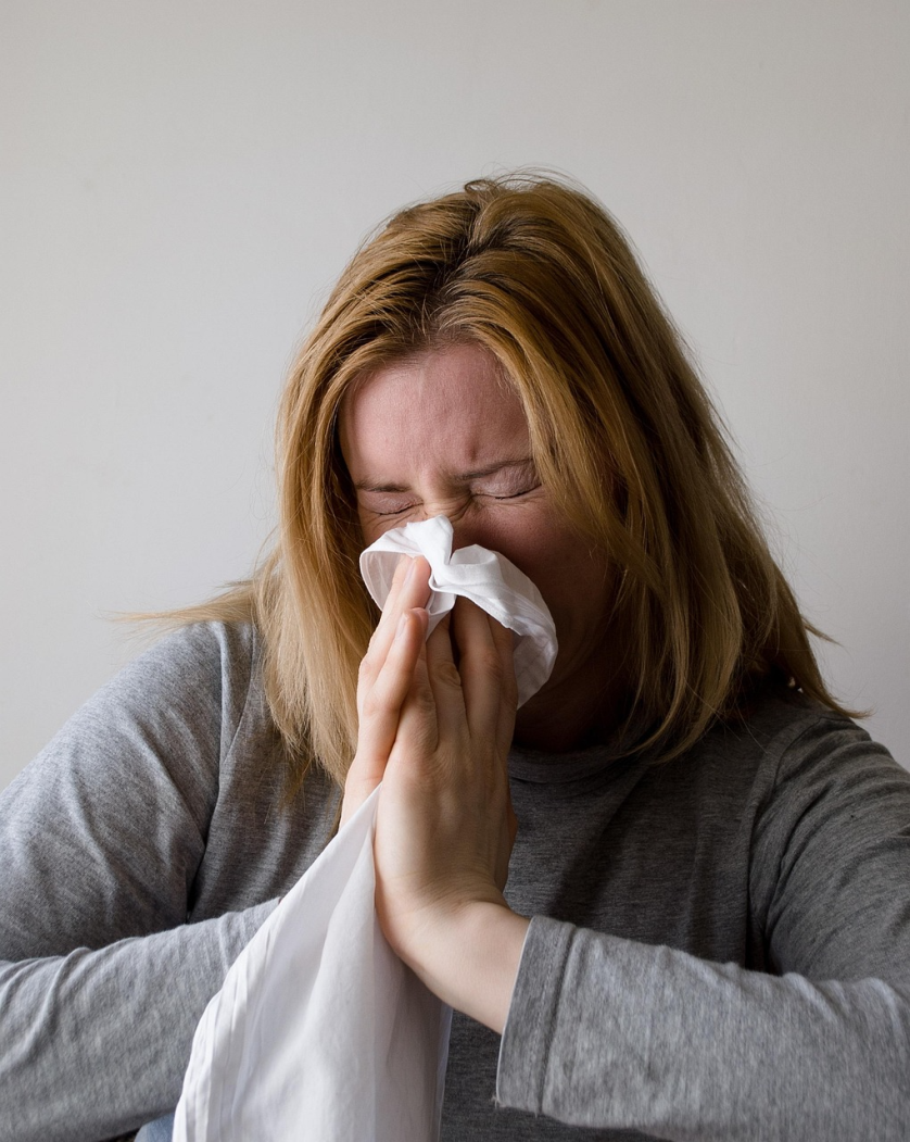woman sneezing showing symptoms of winter illness