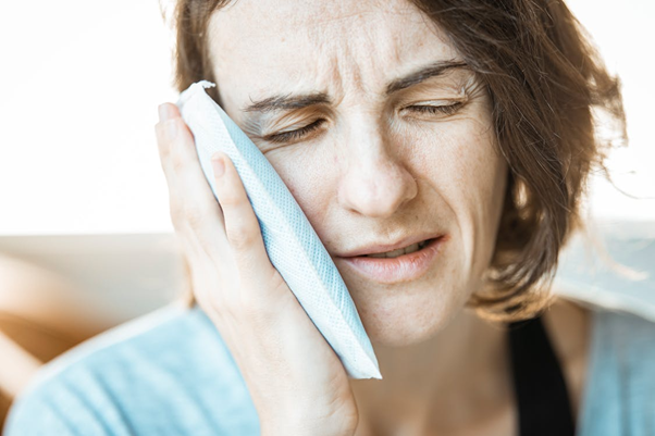 Woman applying a cold compress to her face