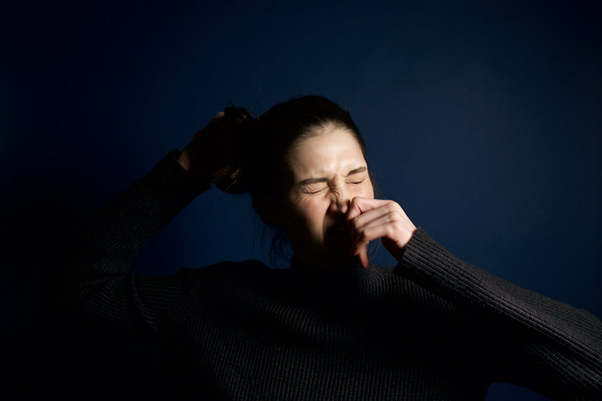 Woman touching her nose indoors