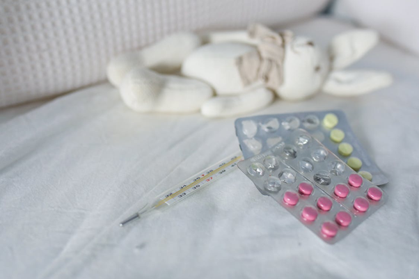 Thermometer and pills placed on a bed