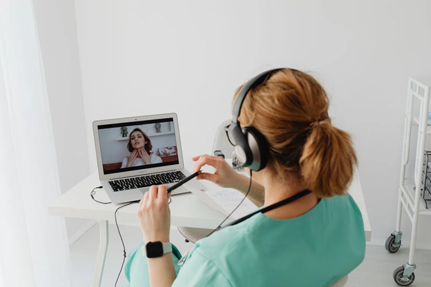 a doctor in scrubs taking an online video call with a patient suffering from a sore throat