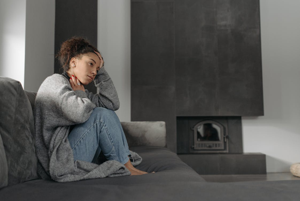 Sick woman sitting on a sofa wrapped in a blanket