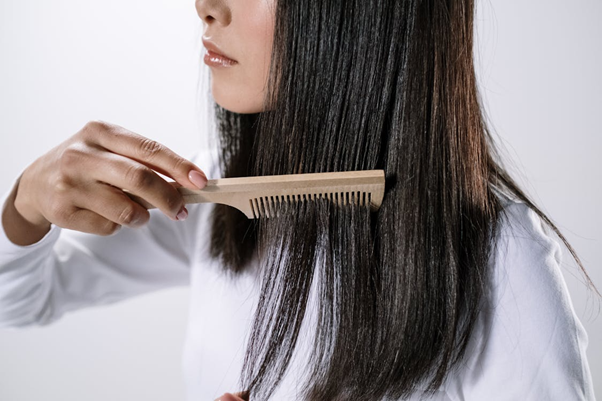 Woman holding a wooden hair comb near her scalp