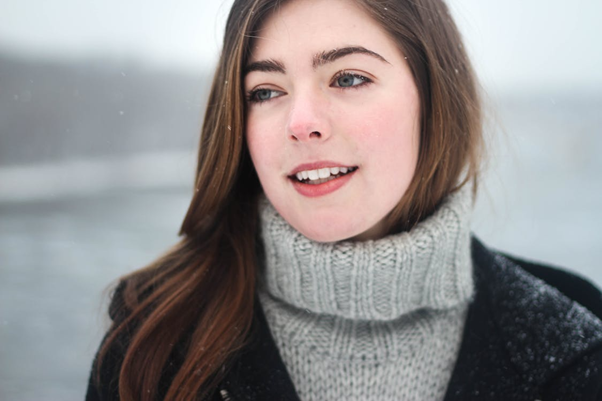 Woman in a grey sweater sitting quietly indoors