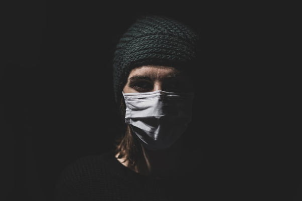 Woman wearing a knit beanie and face mask outdoors