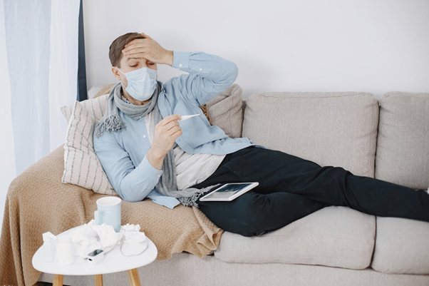Man sitting on a couch appearing fatigued and unwell
