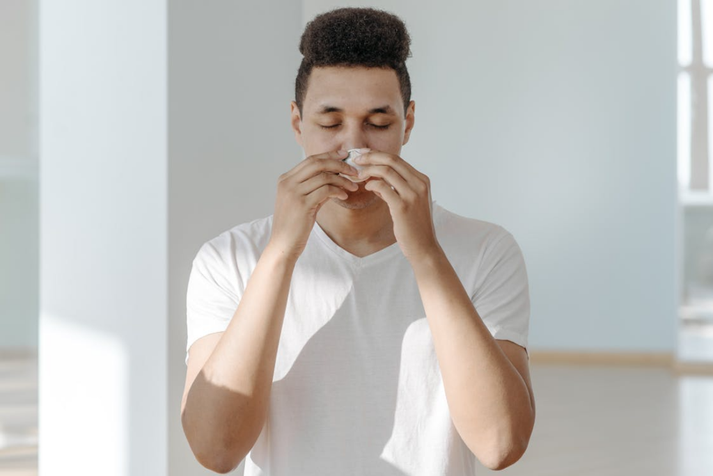 A person wiping their nose with a tissue. 