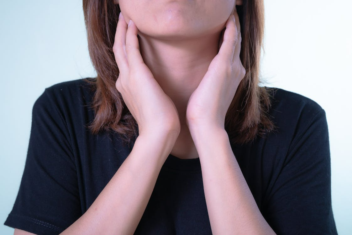 Person touching throat while experiencing severe sore throat symptoms