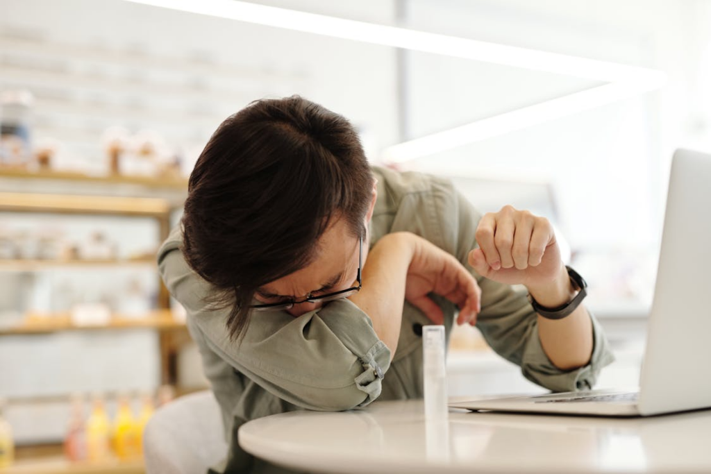 A person coughing in their sleeve. 
