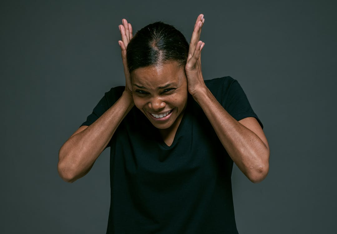 person holding ears in discomfort