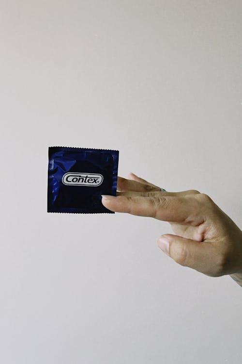 A person holding a packet of condom in their hands. 