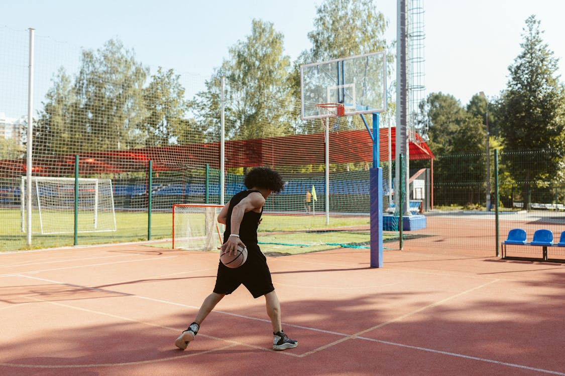 A person holding a basketball in their hands and walking in a court.