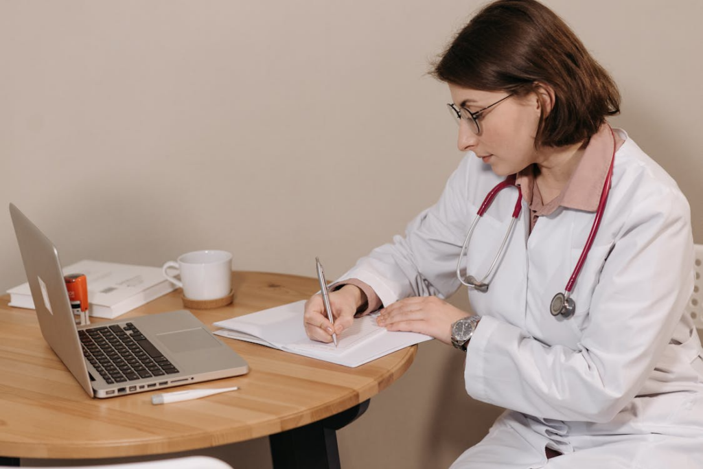 This image shows a doctor seated at a table and reviewing documents.