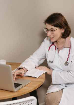 This image shows a female doctor using a laptop during a virtual medical consultation.