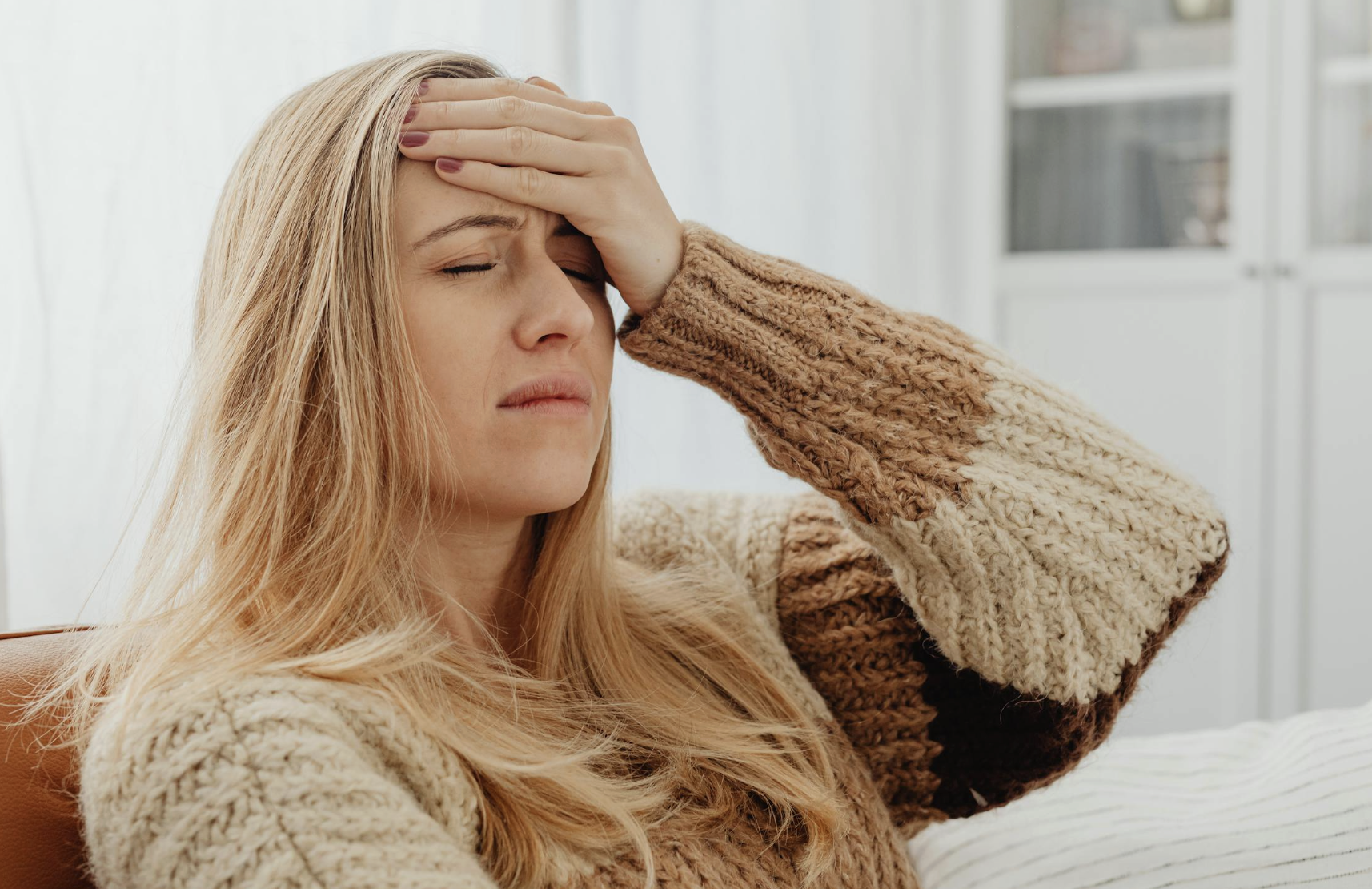 This photo shows a woman holding her forehead while feeling a mild headache.